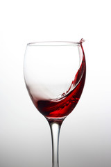 Splash of red wine in a crystal glass on a white background close-up