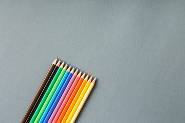 colored pencils in row on a gray background top view.