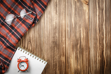 Red alarm clock on notepad on wooden background