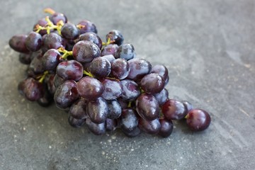 A bunch of ripe blue grapes close-up on a blue concrete shabby background