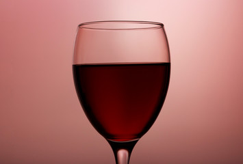 Wineglass with red wine close-up isolated on pink gradient background