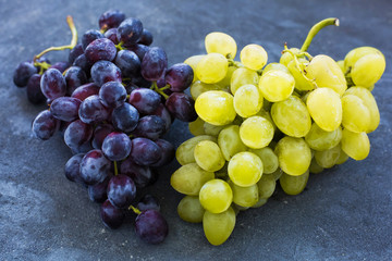 Bunches of ripe green and blue grapes close-up on a blue shabby concrete background