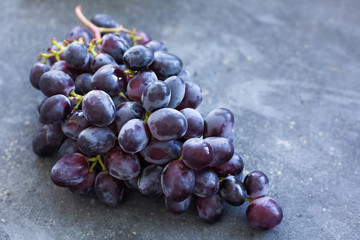 A bunch of ripe blue grapes close-up on a blue concrete shabby background