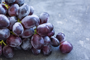 A bunch of ripe blue grapes close-up on a blue concrete shabby background