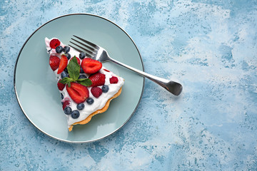 Plate with slice of tasty berry pie on color background