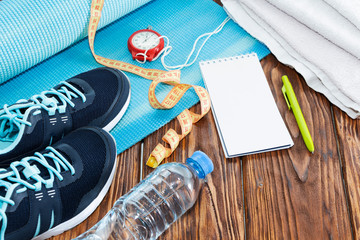 Healthy lifestyle and sports background. Sports shoes, Notepad and pen, stopwatch and water bottle on wooden background with copyspace, top view.