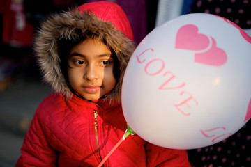 Child holding a balloon with love sign and the text love