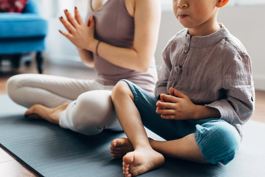 Young mother and son playing yoga at home