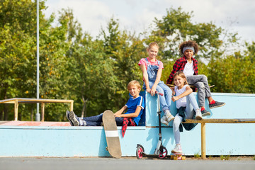 Portrait of group of friends spending time together on fresh air they sitting on the bench and...