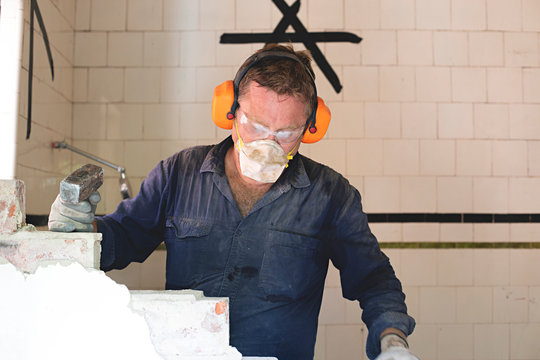 Demo Day - Male tradesman hard at work demolishing a brick wall