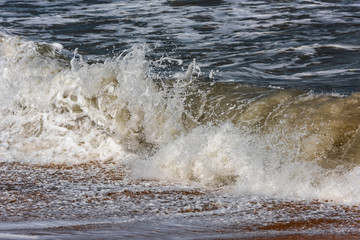 Fototapeta na wymiar Storm at sea, big foamy waves breaking on shore