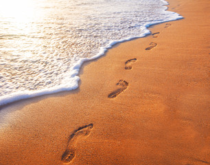 Obraz na płótnie Canvas beach, wave and footprints at sunset time