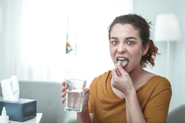Green-eyed woman taking pills while having strong allergy