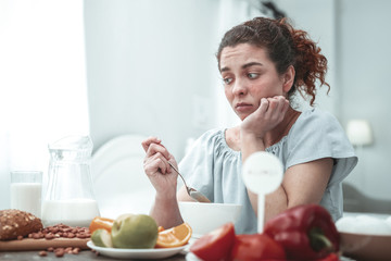 Curly woman sitting in kitchen having allergy to peanuts