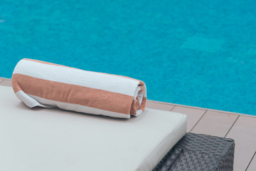Roll soft towel on a sun bed near a swimming pool.