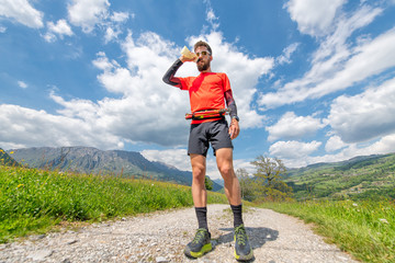 Naklejka premium Man drinks from a water bottle during a trail in the mountains