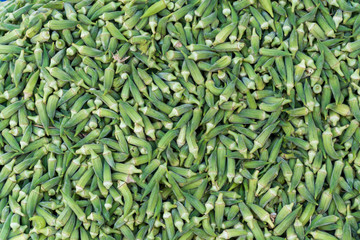 Okra vegetables stacked on a surface as background.