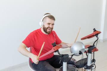 People, music and hobby concept - Man dressed in red t-shirt playing on the electronic drum set