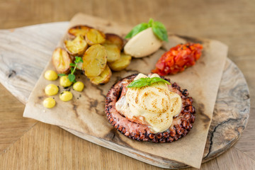 Roasted octopus BBQ with Baked potato. Wooden plate. Restaurant menu