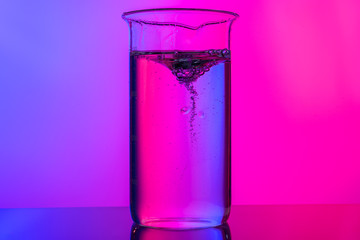 Chemical glassware close up on neon pink-purple background