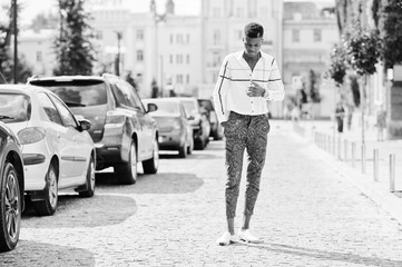 Portrait of handsome stylish african american model man in red throusers and white shirt posed at street.