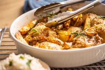 Chicken legs roasted with american potatoes in baking dish