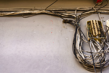 Cable power cords in tangled mess on wall outdoor