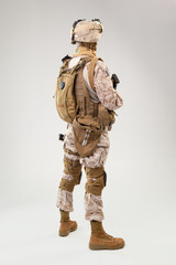 Soldier in US marines uniform with rifle on light grey background, studio shot