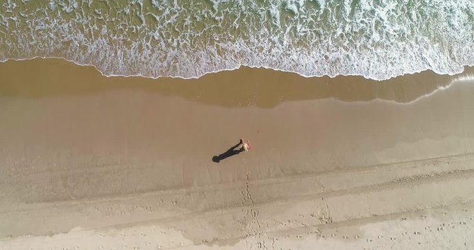 Dron vuela encima vertical sobre mujer que entra al agua