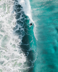 Aerial sport action shot of a surfer at sunrise riding a wave in a blue ocean in Sydney, Australia...