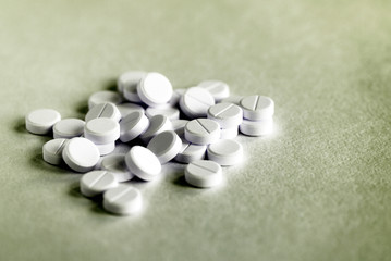 White pills tablets scattered on a paper surface close up