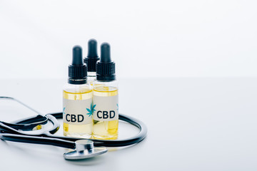cannabis oil in bottles with lettering cbd and stethoscope on white background