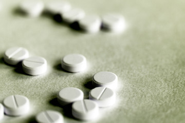White pills tablets scattered on a paper surface close up