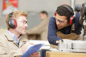 young man and teacher working with noisy machinery
