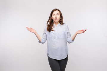Studio portrait of brunette woman in casual clothes showing puzzlement or confusion and reacting...