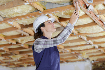 female builder working on wooden ceiling supports