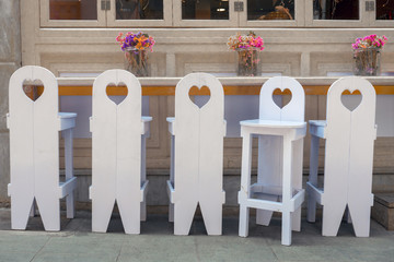 Concept of diversity: six wooden white chairs near the table with simple decor on it. Unique and...