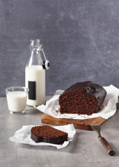 Slice of homemade dark chocolate bread cake with milk on a white parchment paper. Selective focus. Copy space.
