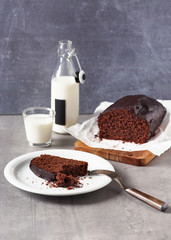 Slice of homemade banana bread with dark chocolate icing on a white pate. Selective focus. Copy space.