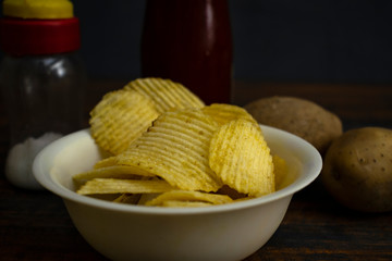 Chips in the bowel in the background sauce and salt bottle 