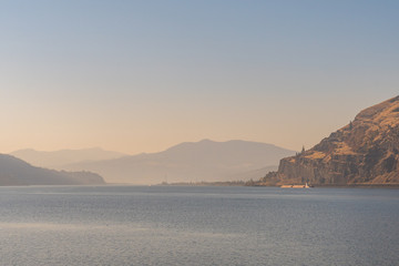 A cargo ship at dusk in the columbia river that serves as a border between the states of Washington and Oregon