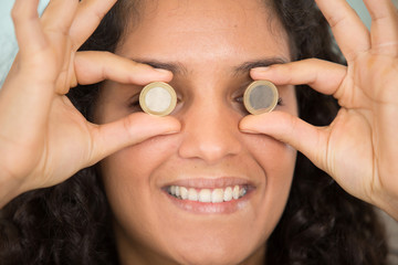 young woman holding a euro coin over each eye