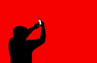 Man in hoodie with a phone isolated on red background. Addicted to the internet and social...
