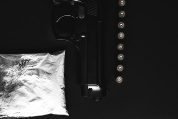 Gun with bullets lying on the table. Criminal problems. Drugs and on black background. Illegal selling. - obrazy, fototapety, plakaty