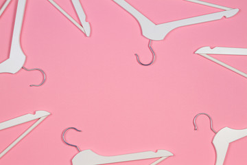 White wooden clothes hangers on pastel pink background. Shopping, sale, promo, social media, new...