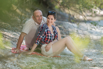 portrait of couple sat on river bank