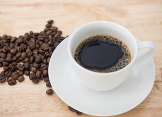 Hot black coffee on white cup with coffee beans.