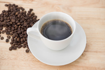 Hot black coffee and smoke on white cup with coffee beans