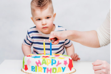 little baby watches his mom light candles on the cake