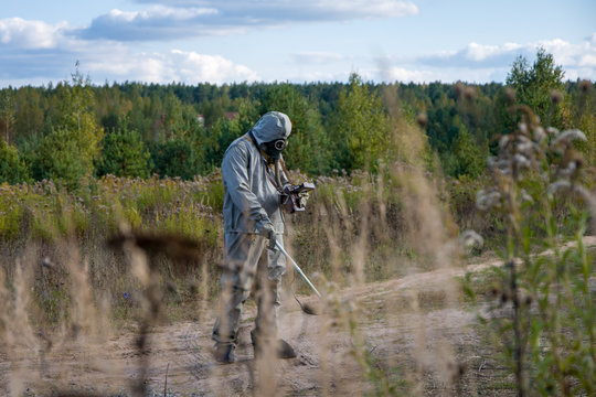 Military in a protective suit checks the level of radiation on the road dosimeter, radiation hazard, military dosimetrists